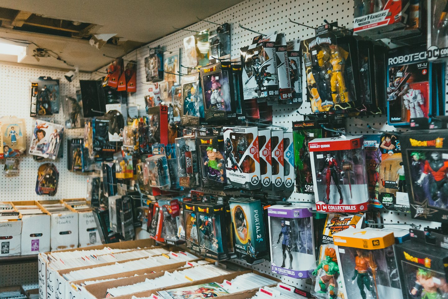 Comic book store interior with many collectible figures and boxes of comics.