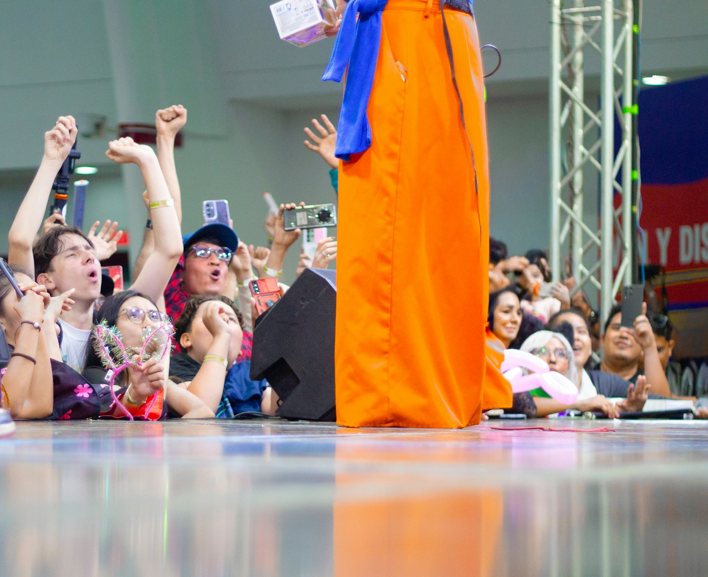 Audience members hold up smartphones toward a performer on stage.