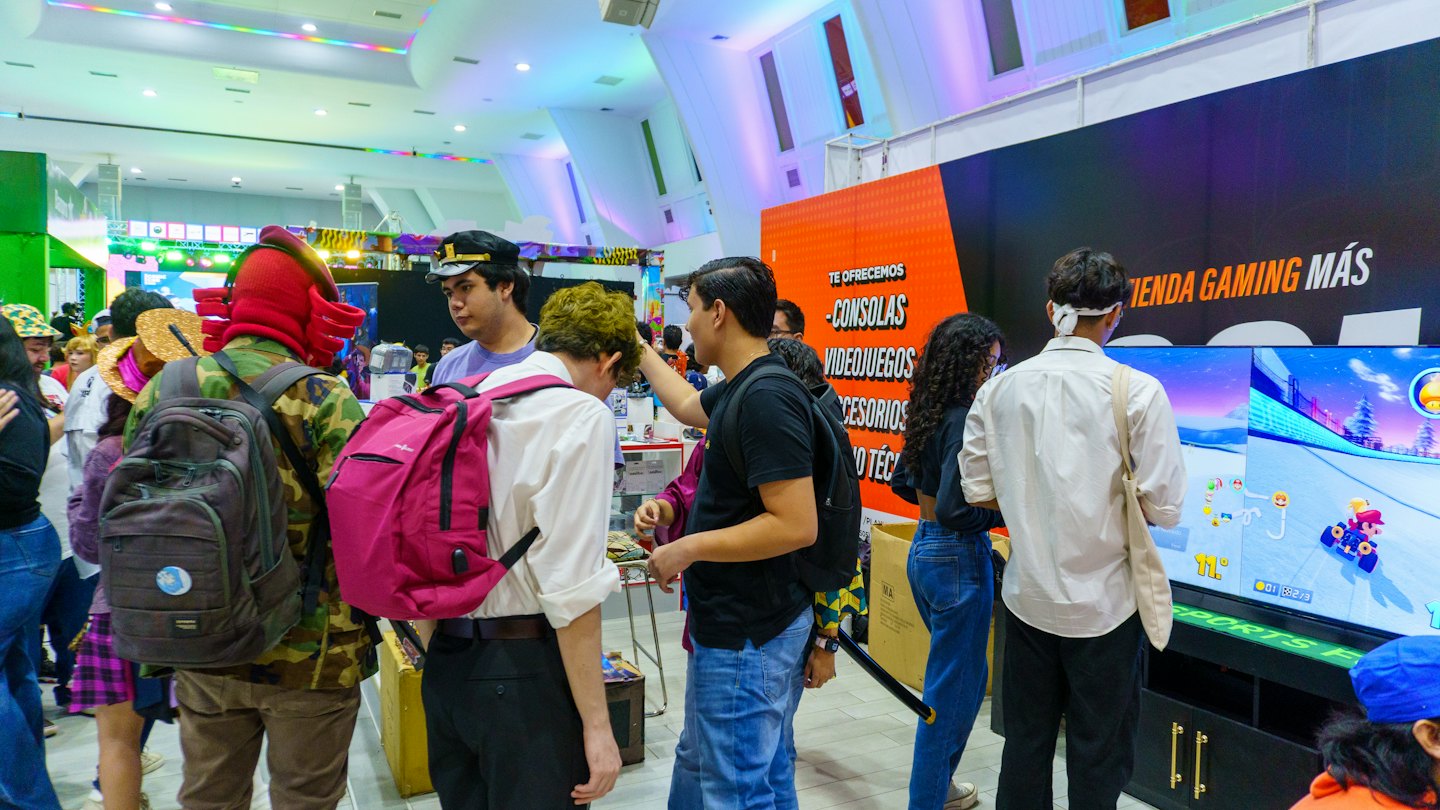People in costumes gather to watch a racing video game.