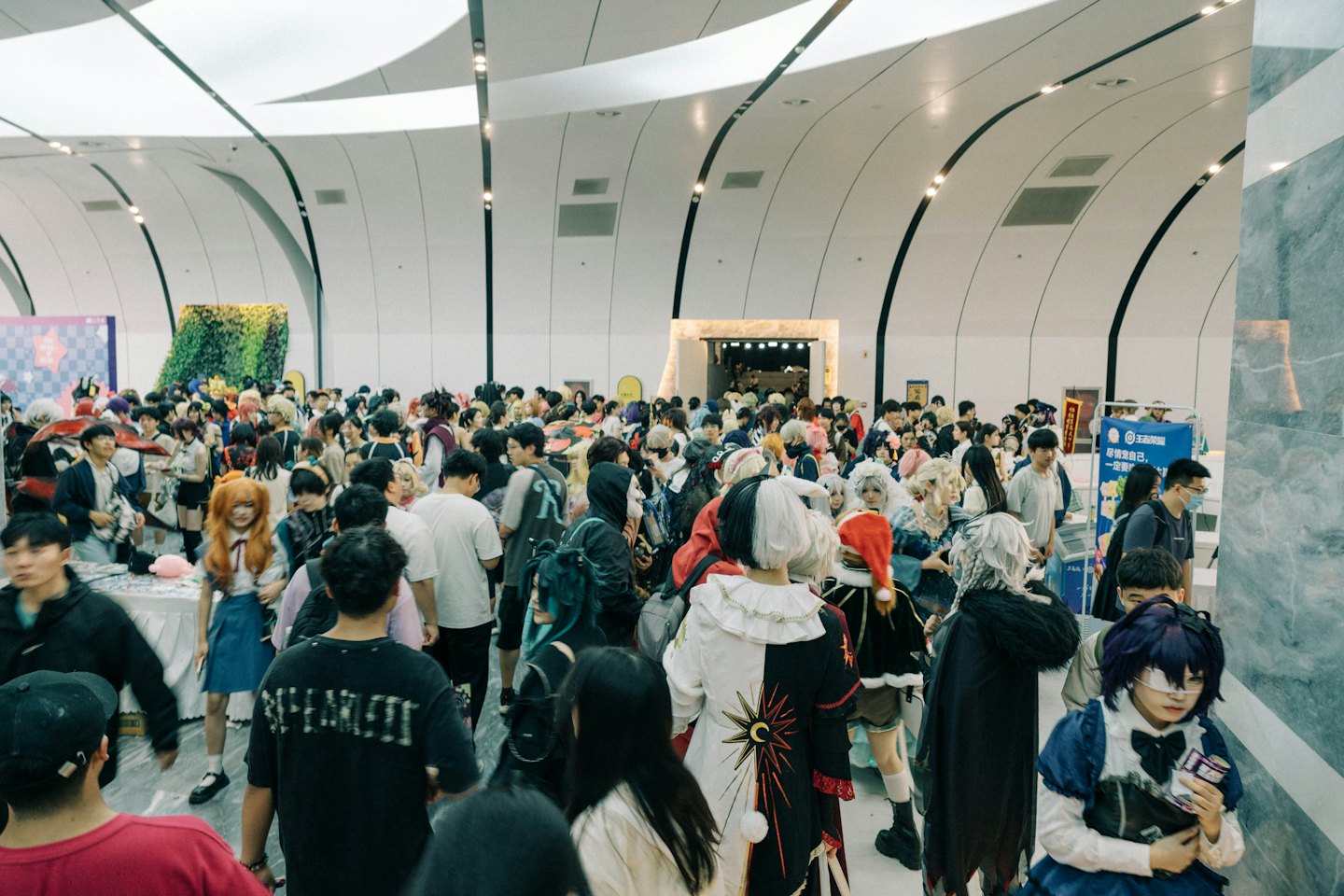 People in cosplay costumes walk through a modern convention hall.